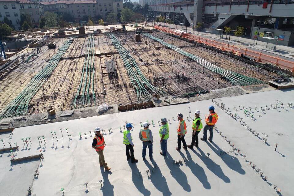 group of 7 construction works overseeing their newly built foundation for the construction of a new building